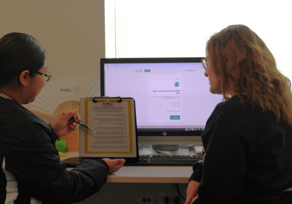 two students sitting next to each other, one is holding a clipboard