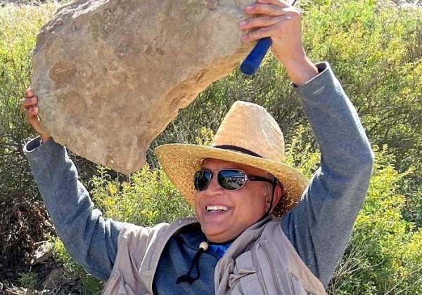 A man with sunglasses holding a rock smiling 