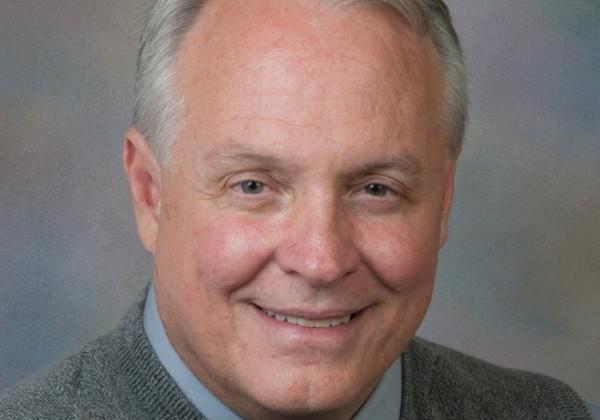 A portrait of a man with grey hair smiling. 