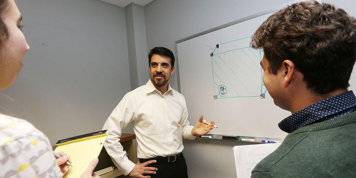 Professor Rodriguez by White Board as students take notes