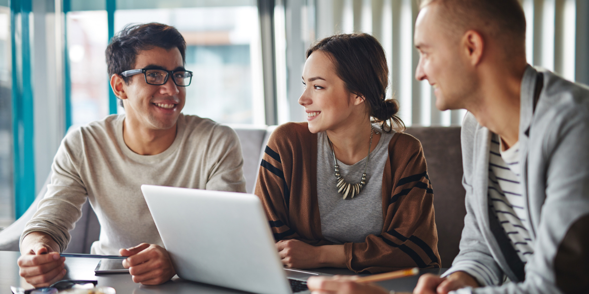 3 people in office conversing at desk