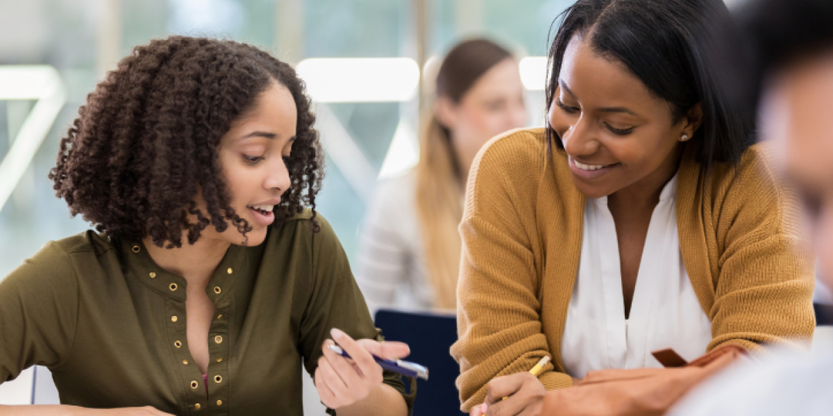 Female teacher and female student at desk.