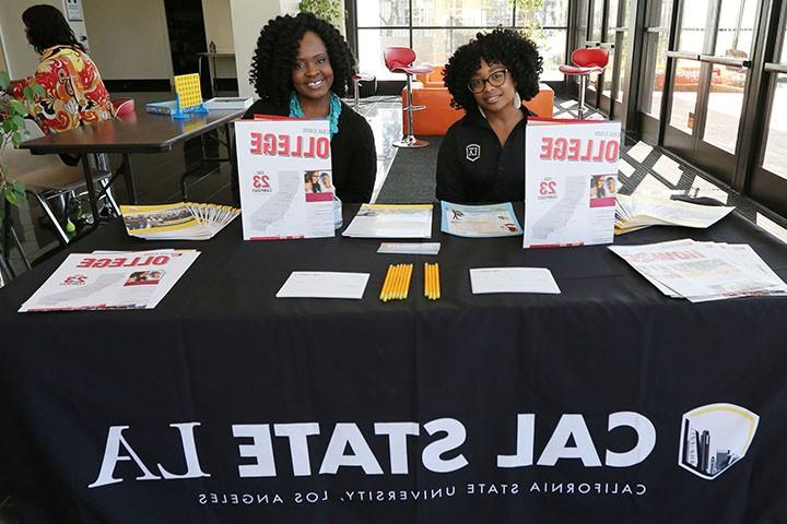 2 students sitting at a table promoting Cal State LA