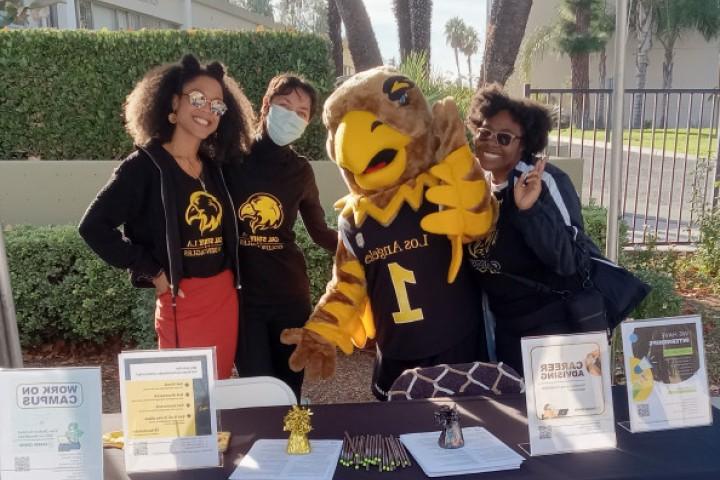 Career advisors, students and campus mascot Eddie smile while at a booth outside the Career Center