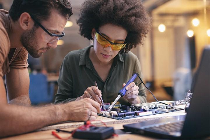 Female and male electrical engineers working on circuit board