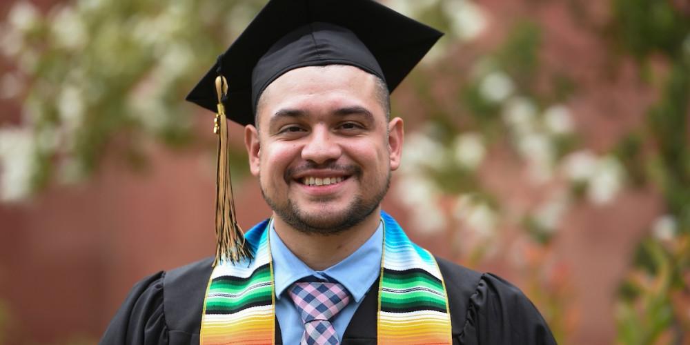 Male graduate wearing black cap and gown.