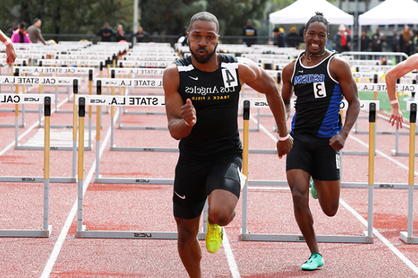 Image of a Cal State LA track star leading a hurdle race. 