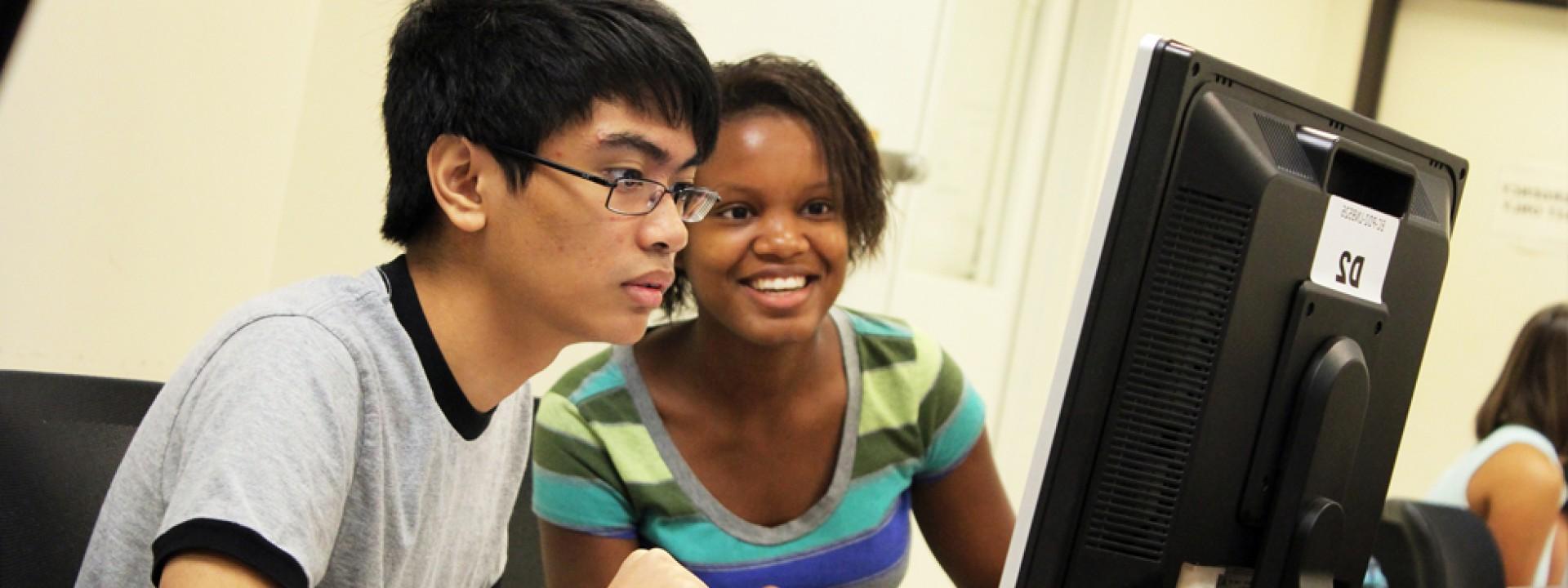 Two Honors College students facing a computer screen intently. 